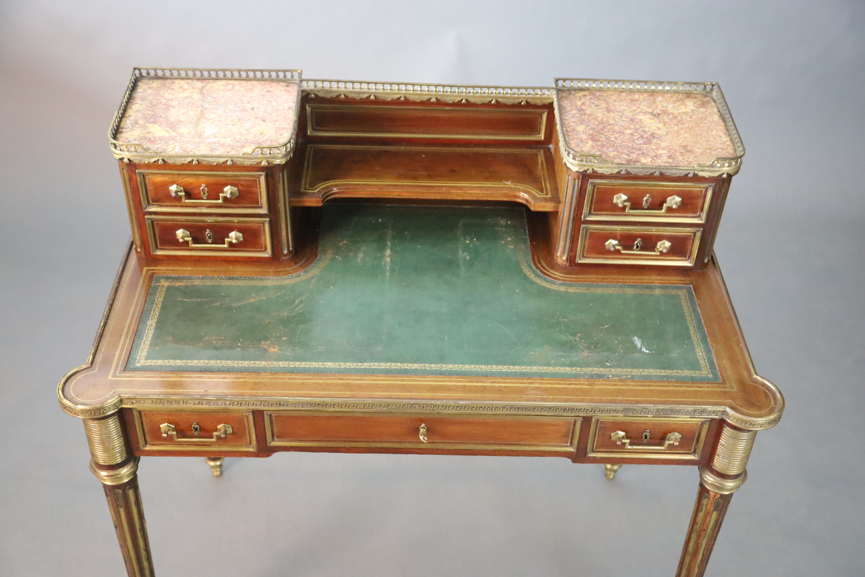 A French Louis XVI style brass mounted marble inset mahogany writing table, W.101.5cm D.7.5cm H.93.5cm